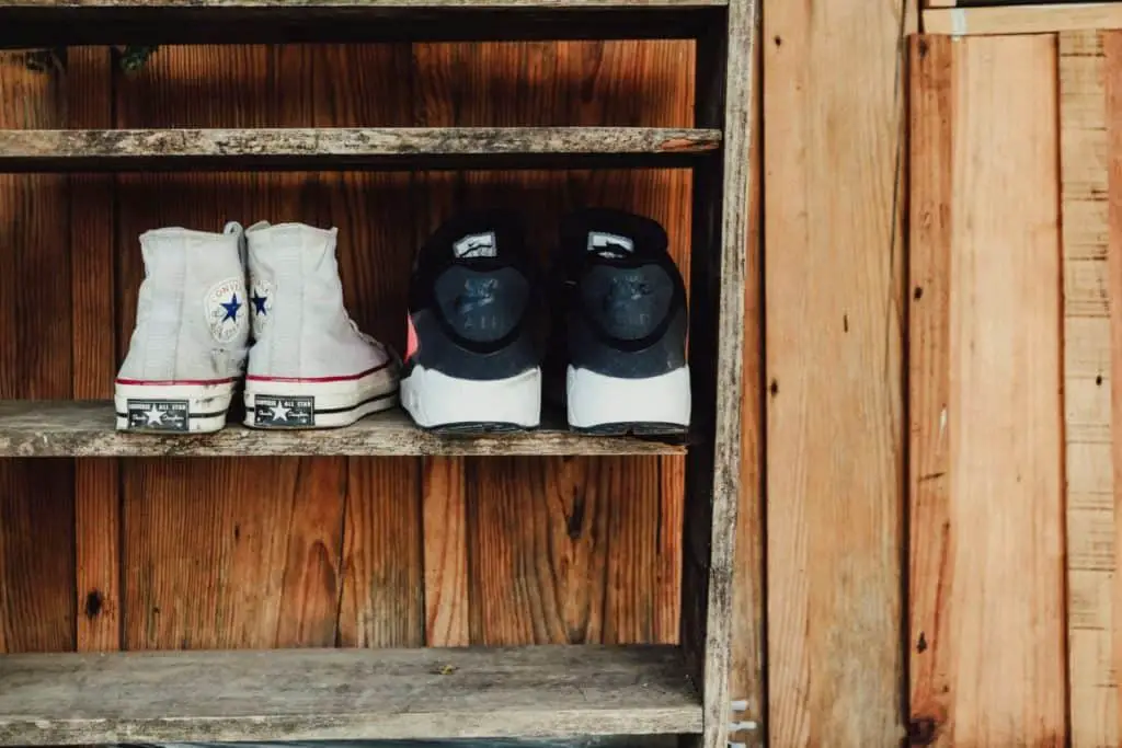 Two pairs of shoes in a shoe rack at the entrance of a yoga studio.